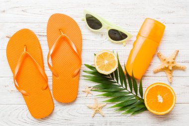 Arka planda plaj aksesuarları olan parmak arası terliklerin üst görünümü. Tropik yaz tatili konsepti.