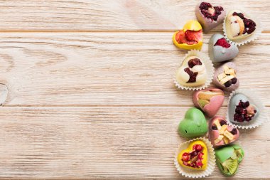 chocolate sweets in the form of a heart with fruits and nuts on a colored background. top view with space for text, holiday concept.