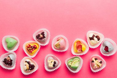 chocolate sweets in the form of a heart with fruits and nuts on a colored background. top view with space for text, holiday concept.