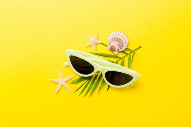 Masa arkasında deniz kabuğu olan güneş gözlükleri. Yaz arkaplanında güneş gözlüğü. Metin için kopyalama alanı olan üst görünüm düzlüğü.