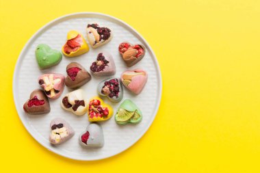 Plate with different chocolate on colored background. Assortment of fine chocolates top view vith copy space Health and obesity concept.