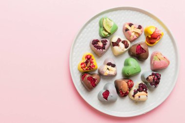 Plate with different chocolate on colored background. Assortment of fine chocolates top view vith copy space Health and obesity concept.