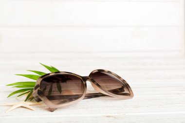 Masa arkasında deniz kabuğu olan güneş gözlükleri. Yaz arkaplanında güneş gözlüğü. Metin için kopyalama alanı olan üst görünüm düzlüğü.
