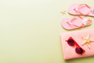 Yaz güneşlenme sahili arka planı, güneş gözlükleri, parmak arası terlikler ve havlu, metin için fotokopi alanı olan üstten manzara.