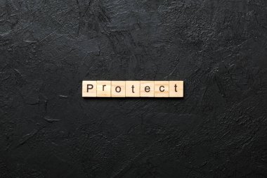 Tahta bloğa yazılmış bir kelime. Deksing, konsept için çimento masa üzerinde PROTECT metin.