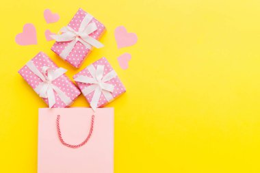 Gift boxes pop out from paper bag top view on colored background. bag packing handmade boxes fall out Concept of holidays, shopping, sale, discounts. Top view, flat lay.