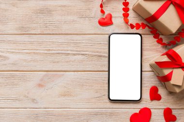 mobile phone with blank screen on colored background with hearts, valentine day concept top view flat lay.