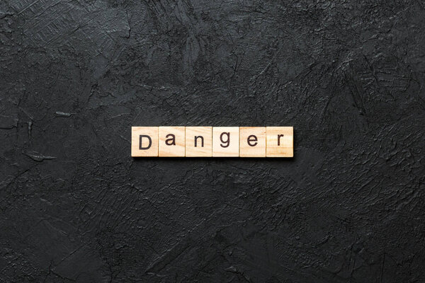 Danger word written on wood block. Danger text on cement table for your desing, Top view concept.