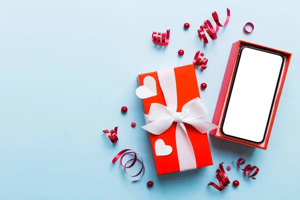 Opened gift box with ribbon and phone on color background, top view. Blank open box packaging mockup , Template for your design - branding mockup.