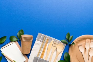 Açık beyaz masa arkaplanındaki boş, tek kullanımlık çevre dostu tabaklar, bardaklar, çatal bıçaklar. Üst Manzara. Biyo-çözünebilir el yapımı yemekler. Geri dönüşüm konsepti. Yakın plan..