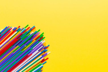 Renkli arka planda renkli plastik pipetler, düz yatış. Metin için Boşluğu Kopyala.