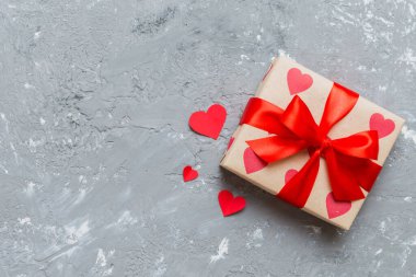 Top view photo of valentine day decorations gift box with red ribbon bow on colored background. Holiday gift boxes with top view.