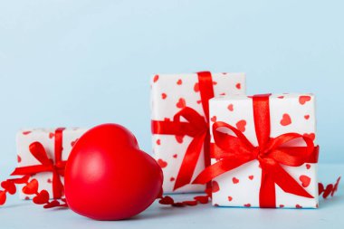 gift box with red bow and red heart on colored background. Perspective view. Flat lay.
