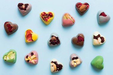 chocolate sweets in the form of a heart with fruits and nuts on a colored background. top view with space for text, holiday concept.