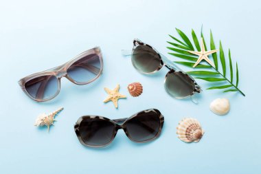Masa arkasında deniz kabuğu olan güneş gözlükleri. Yaz arkaplanında güneş gözlüğü. Metin için kopyalama alanı olan üst görünüm düzlüğü.