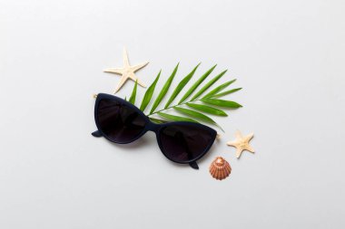 Masa arkasında deniz kabuğu olan güneş gözlükleri. Yaz arkaplanında güneş gözlüğü. Metin için kopyalama alanı olan üst görünüm düzlüğü.