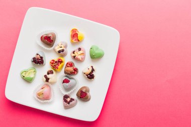 Plate with different chocolate on colored background. Assortment of fine chocolates top view vith copy space Health and obesity concept.