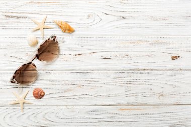 Masa arkasında deniz kabuğu olan güneş gözlükleri. Yaz arkaplanında güneş gözlüğü. Metin için kopyalama alanı olan üst görünüm düzlüğü.