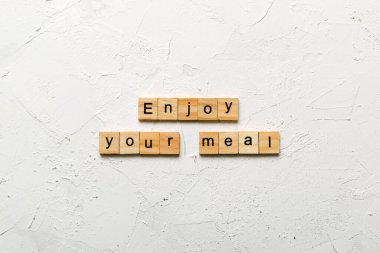 Tahta blokta yazan yemek kelimenizin tadını çıkarın. Çimento masasındaki yemek metninin tadını çıkar..