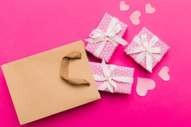 Gift boxes pop out from paper bag top view on colored background. bag packing handmade boxes fall out Concept of holidays, shopping, sale, discounts. Top view, flat lay.