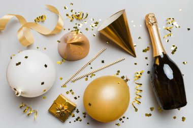 Renkli arka planda şampanya şişesi hediye paketi kurdeleleri ve konfetilerin düz kompozisyonu vardı. Düz konum, üst görünüm tatil konsepti.