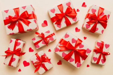 Top view photo of valentine day decorations gift box with red ribbon bow on colored background. Holiday gift boxes with top view.