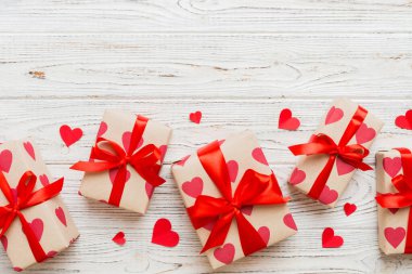 Top view photo of valentine day decorations gift box with red ribbon bow on colored background. Holiday gift boxes with top view.