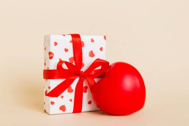 gift box with red bow and red heart on colored background. Perspective view. Flat lay.