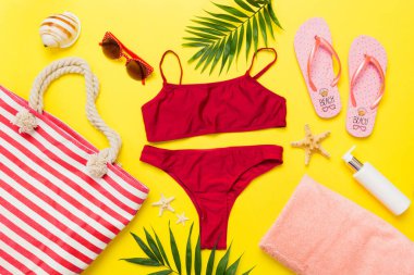 Kadın mayosu ve plaj aksesuarları düz manzarada yatıyordu. Renkli arka planda bikinili üst manzara. Tatil kavramı kopyalama alanı.