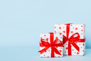 gift box with red bow and red heart on colored background. Perspective view. Flat lay.