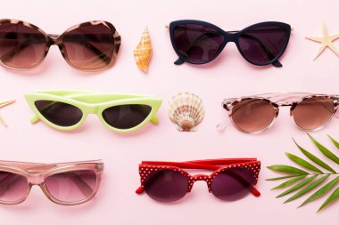 Masa arkasında deniz kabuğu olan güneş gözlükleri. Yaz arkaplanında güneş gözlüğü. Metin için kopyalama alanı olan üst görünüm düzlüğü.