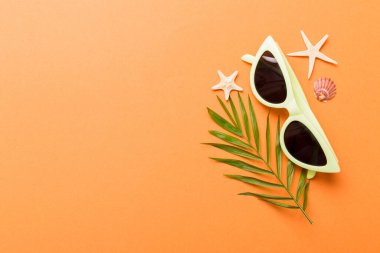 Masa arkasında deniz kabuğu olan güneş gözlükleri. Yaz arkaplanında güneş gözlüğü. Metin için kopyalama alanı olan üst görünüm düzlüğü.