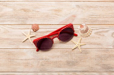 Masa arkasında deniz kabuğu olan güneş gözlükleri. Yaz arkaplanında güneş gözlüğü. Metin için kopyalama alanı olan üst görünüm düzlüğü.