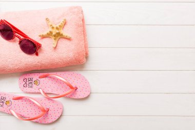 Yaz güneşlenme sahili arka planı, güneş gözlükleri, parmak arası terlikler ve havlu, metin için fotokopi alanı olan üstten manzara.