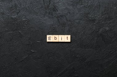 Tahta blokta EBT kelimesi yazıyor. Vergilerden Önce Kısaltma Kazancı desing, konsept için çimento masa üzerinde metin.