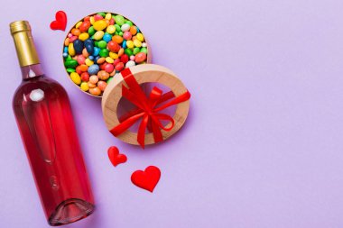 Sevgililer Günü için renkli arka planda bir şişe kırmızı şarap hediye ve çikolatalı. Kalp, hediye kutusuyla şekillendirilmiş çikolatalar fotokopi alanı ile üst görünüm.