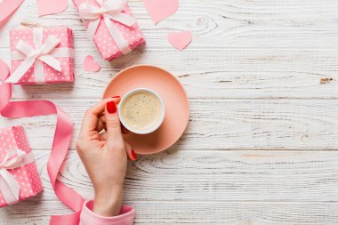 Flat lay of heart shaped cup of black coffee in the hands of women on colored background with copy space top view. Valentine day and holiday concept.