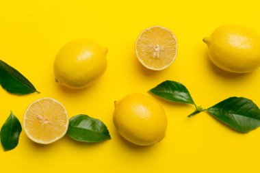 Renkli arka planda yeşil yapraklı taze limonlar, üst görünüm, metin için boşluk.