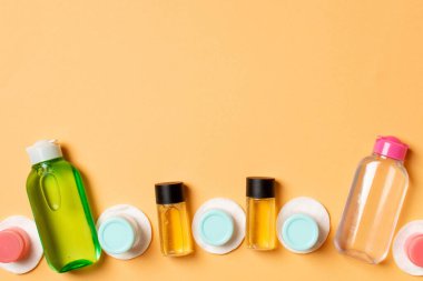 Renkli arka planda seyahat etmek için bir grup küçük şişe. Fikirlerin için uzayı kopyala. Kozmetik ürünlerin düz bileşimi. Pamuklu krema kaplarının üst görüntüsü.