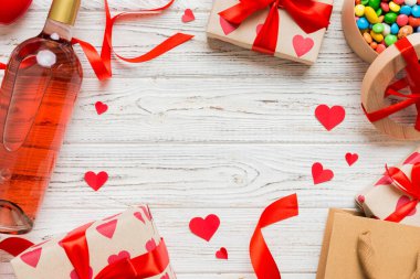 top view photo of st valentine day decor shopping, bag, wine, bottle, envelope, gift, box, candy and red heart on colored background with empty space. Frame background.