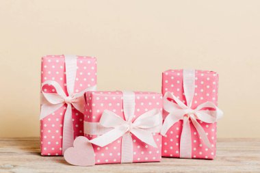 gift box with red bow and red heart on colored background. Perspective view. Flat lay.