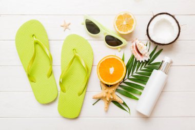 Arka planda plaj aksesuarları olan parmak arası terliklerin üst görünümü. Tropik yaz tatili konsepti.