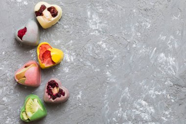 chocolate sweets in the form of a heart with fruits and nuts on a colored background. top view with space for text, holiday concept.