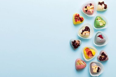 chocolate sweets in the form of a heart with fruits and nuts on a colored background. top view with space for text, holiday concept.