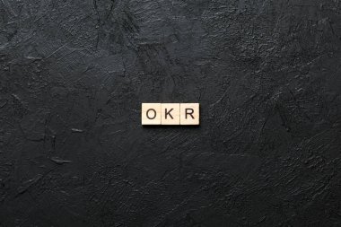 Tahta blokta OKR kelimesi yazıyor. Objective Key 'in kısaltması çimento masadaki metin desing, konsept için.