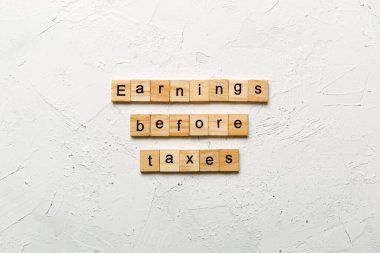 Earnings Before Taxes word written on wood block. abbreviation EBT text on cement table for your desing, concept. clipart