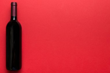 Renkli masada bir şişe kırmızı şarap. Düz konum, üst görünüm kopyalama alanı.