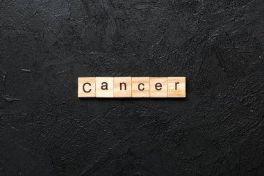 Kanserli kelime ahşap blokta yazılı. Deksing, konsept için CANCER metin çimento masa üzerinde.