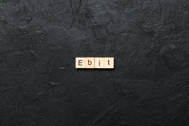 Tahta blokta EBT kelimesi yazıyor. Vergilerden Önce Kısaltma Kazancı desing, konsept için çimento masa üzerinde metin.