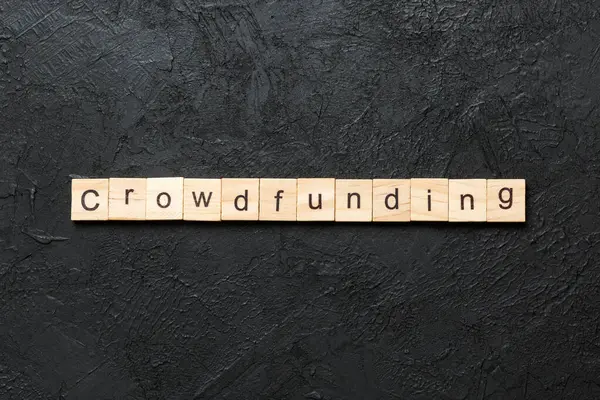 stock image CROWDFUNDING word written on wood block. CROWDFUNDING text on cement table for your desing, concept.